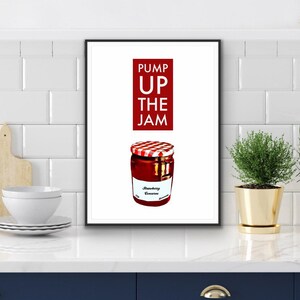 Puede incluir: Una impresi&oacute;n enmarcada que presenta un tarro de conserva de fresa con una tapa a cuadros rojos y blancos. El texto "PUMP UP THE JAM" est&aacute; encima del tarro en un rect&aacute;ngulo rojo. El tarro tiene una etiqueta blanca que dice "Strawberry Conserve".