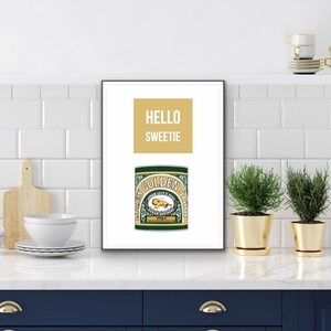May include: A white framed print with the text "HELLO SWEETIE" in yellow and a green and gold Lyle's Golden Syrup can.