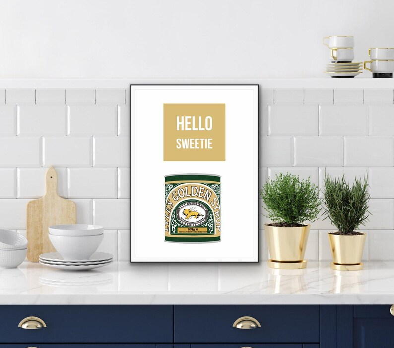 May include: A white framed print with the text "HELLO SWEETIE" in yellow and a green and gold Lyle's Golden Syrup can.