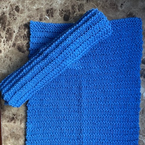 Puede incluir: Un paño de cocina de punto azul con un paño de cocina de punto azul a juego. El paño de cocina está doblado por la mitad y el paño de cocina está encima.