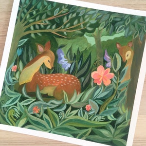 May include: A square art print featuring a painted scene of a brown fawn with white spots resting in a lush green forest. The composition includes dense foliage, large green leaves, a prominent pink flower, smaller orange blossoms, and a second deer.