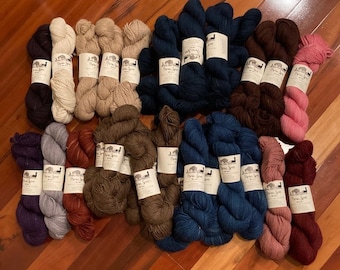 Könnte beinhalten: Sortiment von 20 Garnknäuel in verschiedenen Farben, darunter Braun, Blau, Grau und Rosa. Jedes Knäuel ist mit "Peruvian Spin" gekennzeichnet.