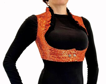 Può includere: Un gilet di paillettes con un colletto a volant e una scollatura bassa. Il gilet è arancione e ha una chiusura a bottone sul davanti.