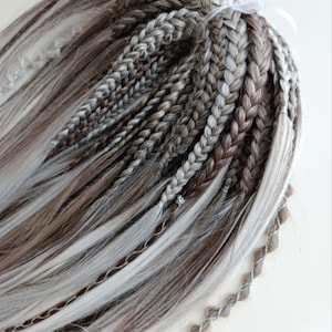 May include: A set of braided hair extensions in shades of brown and white. The extensions are tied together with a white ribbon.