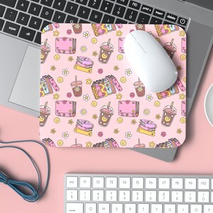 May include: A pink mouse pad with a repeating pattern of books, coffee cups, and flowers. The mouse pad is designed for use with a computer mouse.
