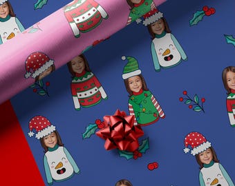 May include: Christmas-themed wrapping paper featuring a repeating pattern of a child's face wearing a festive sweater and hat. The design includes a snowman sweater, a red and white sweater, and a green sweater with lights. The background is a deep blue color.