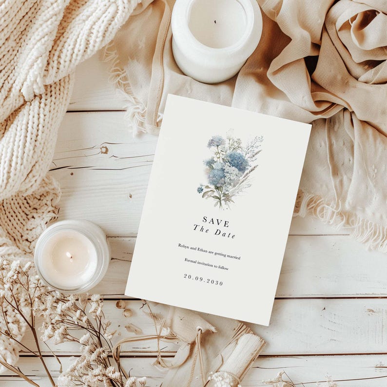 May include: A rectangular Save the Date card featuring a blue floral illustration, with the text: Save The Date, Robyn and Ethan are getting married, Formal invitation to follow, 20.09.2030. The card is printed on off-white paper with black text.
