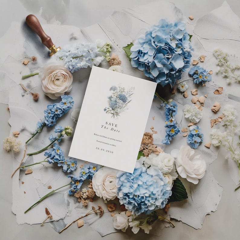 May include: A white rectangular Save the Date card featuring a blue floral illustration, with the text "SAVE The Date", "Robin and Yohan are getting married", "Formal invitation to follow", and the date "20.09.2030" surrounded by blue hydrangeas.