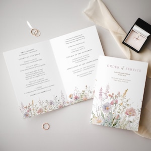 Könnte beinhalten: Ein Programm für eine Hochzeitszeremonie mit einem floralen Design mit rosa, lila und weißen Blumen. Der Text enthält die Namen "Gabrielle und William" und das Datum "20/09/2020".