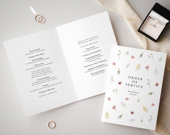 May include: A white wedding ceremony order of service booklet with a floral design. The booklet includes the order of service, the names of the bride and groom, and the date of the wedding.