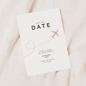 May include: Save the date card with a pink airplane flying over a dotted line that forms a heart shape. The text reads "Save the Date", "Lucinda & Jeremy are getting married", "20/09/2030", "Italy", and "Formal Invitation to Follow".