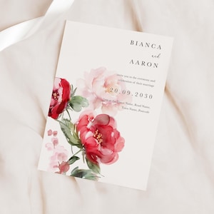 May include: Wedding invitation with a watercolour floral design featuring pink and red flowers. The invitation reads "Bianca and Aaron invite you to the ceremony and celebration of their marriage 20.09.2030 7pm at the Venue Name, Road Name, Town Name, Postcode"