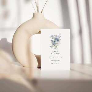 May include: A rectangular white Save the Date card featuring a blue floral illustration, the text "SAVE The Date", "Robyn and Ethan are getting married", "Formal invitation to follow", and the date "20.09.2030" in black serif and sans-serif fonts.