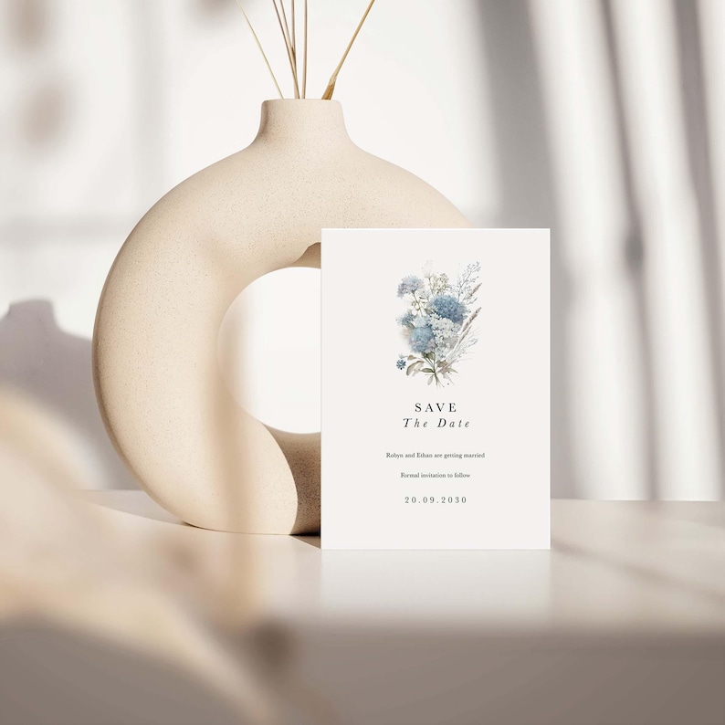 May include: A rectangular white Save the Date card featuring a blue floral illustration, the text "SAVE The Date", "Robyn and Ethan are getting married", "Formal invitation to follow", and the date "20.09.2030" in black serif and sans-serif fonts.