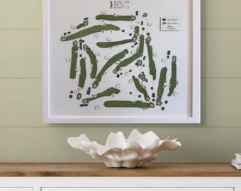 May include: A white framed print of a golf course map for the Penobscot Valley Country Club in Orono, Maine. The map shows the layout of the 18 holes, with green for the fairways, brown for bunkers, and black for tee boxes.