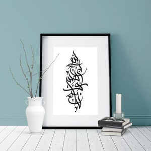 May include: A black and white calligraphy print in a black frame, hanging on a light blue wall. The print features Arabic script in a vertical design.