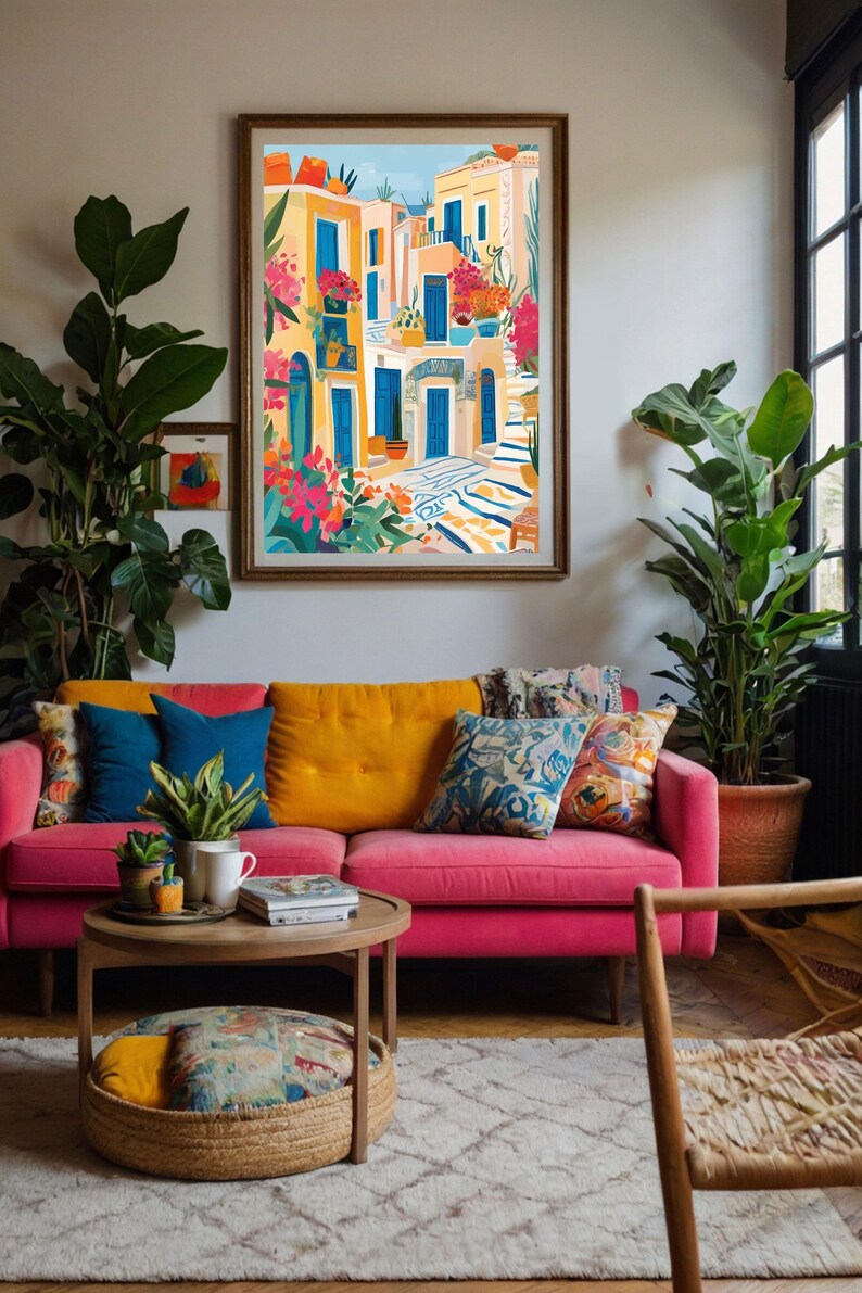 May include: A colorful painting of a narrow street in a Mediterranean village. The buildings are painted in shades of yellow and white, with blue doors and windows. There are potted plants and flowers on the balconies and in the street. The painting is framed in a gold frame and is hanging on a wall in a living room.