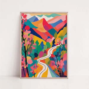 Op de afbeelding: Een ingelijste kunstdruk met een kleurrijk landschapsschilderij. Het kunstwerk toont een kronkelende weg door een levendige bergscène met roze, rode, groene en gele tinten. De print is ingelijst in een lichtgekleurde houten lijst.