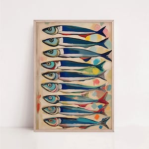 May include: A framed art print showing a row of sardines. The fish are painted in blue with red, yellow, and green details. The background is a light beige with colourful brushstrokes. The frame is a light wood colour.