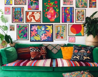 May include: A green velvet sofa with colorful throw pillows and a blanket. The wall behind the sofa is decorated with a gallery wall of framed artwork featuring floral, geometric, and abstract designs in bright colors.