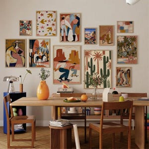 Puede incluir: Una colección de láminas artísticas enmarcadas en varios tamaños y estilos, con paisajes desérticos, figuras y patrones abstractos. La paleta de colores incluye tonos cálidos de naranja, marrón y beige, con toques de azul y verde. Las láminas se exhiben en una pared blanca.