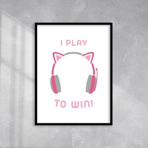 May include: A white framed print with the text "I PLAY" in pink, a pink headset with cat ears, and the text "TO WIN!" in pink.