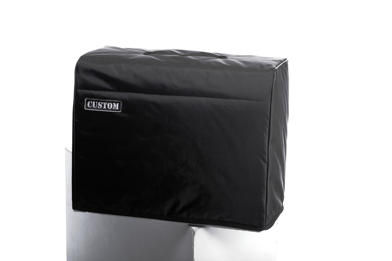 May include: Black amp cover with a zipper and a handle. The cover has the word "CUSTOM" printed on the front.