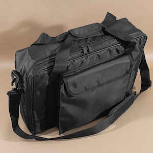 May include: A black nylon travel bag with a zippered top closure, two top handles, and an adjustable shoulder strap. The bag has a front pocket with a zipper closure.
