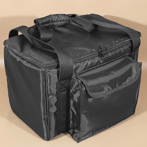May include: Black insulated cooler bag with a zippered top and a front pocket. The bag has a rectangular shape with a handle on top and a shoulder strap. The bag is designed to keep items cold or hot.