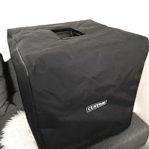 May include: A black, square-shaped cover with a rectangular handle opening on top. The cover has a white "CUSTOM" label on the side. The cover appears to be made of a durable, water-resistant material. The cover is designed to protect an item.
