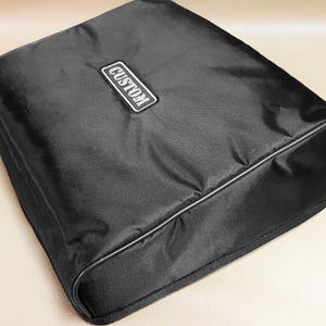Pode incluir: Estojo de transporte preto personalizado com uma etiqueta "CUSTOM" branca.