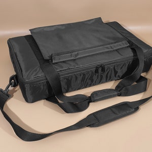 May include: Black padded carrying case with a zippered closure, two top handles, and an adjustable shoulder strap.