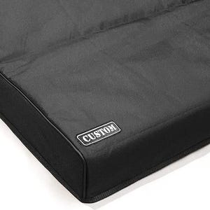 Peut inclure: Housse noire sur mesure de forme rectangulaire. La housse a une surface texturée et une bordure noire. Une petite étiquette rectangulaire avec le mot "CUSTOM" est attachée.