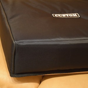 Könnte beinhalten: Schwarze gepolsterte Tasche mit einem weißen "CUSTOM"-Etikett.