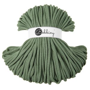Op de afbeelding: Een spoel met saliegroene katoenen koord, gewikkeld in een wit label met de tekst "Bobbiny".