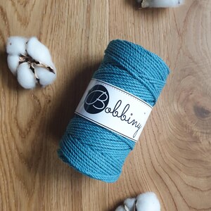 May include: A teal blue cotton rope, wound into a ball, with a white label that says "Bobbiny".
