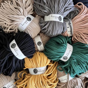 Può includere: Assortimento di corde di cotone colorate in vari colori, tra cui beige, grigio, nero, verde, giallo e rosa. Ogni rotolo è etichettato con il nome del marchio "Bobbiny".