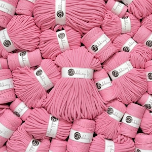 Könnte beinhalten: Eine Ansammlung von pinkfarbenen Baumwollkordelspulen zum Basteln, die jeweils mit einer weißen Papierbanderole mit dem Markennamen Bobbiny versehen sind. Die Kordeln sind in einem dichten, überlappenden Haufen angeordnet.
