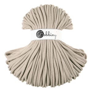 Può includere: Un gomitolo di corda di cotone beige, avvolto in un cerchio, con un'etichetta bianca su cui è scritto "Bobbiny".