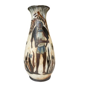 Peut inclure: Un vase en céramique avec un glaçage blanc et un motif peint en brun et bleu. Le vase présente une figure stylisée d'une personne debout dans un champ de fleurs.