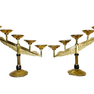 Puede incluir: Un par de candelabros de metal dorado con cinco portavelas cada uno. Los candelabros tienen un diseño decorativo de hojas y enredaderas. La base de cada candelabro es negra.