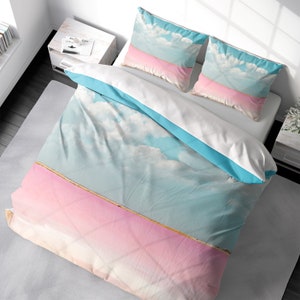 Könnte beinhalten: Ein rosa-blaues Bettwäsche-Set mit einem Wolken- und Himmelsdesign. Der Bettbezug hat einen rosa-blauen Ombre-Effekt mit einer dünnen weißen Linie in der Mitte. Die Kissenbezüge haben ein ähnliches Design mit blauem Himmel und weißen Wolken.