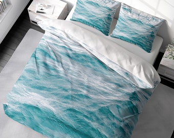 May include: A teal blue and white duvet cover with a wave pattern. The duvet cover is on a bed with two matching pillowcases.