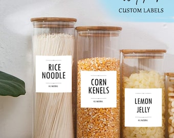 May include: Four glass jars with wooden lids and white labels. The labels have black text that reads "Rice Noodle", "Corn Kenels", "Lemon Jelly", and "All Natural".