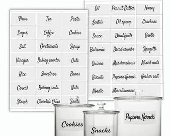 Könnte beinhalten: Drei durchsichtige Glasbehälter mit weißen Etiketten. Die Etiketten lauten "Cookies", "Snacks" und "Popcorn Kernels". Die Behälter stehen auf einer weißen Oberfläche vor einem weißen Blatt Papier mit einem Raster von Etiketten für verschiedene Lebensmittel.