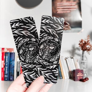 May include: Two black and white bookmarks with a floral design and the text "Moonchild" printed on them. The bookmarks feature a stylized illustration of a moth, a butterfly, and two rabbits.