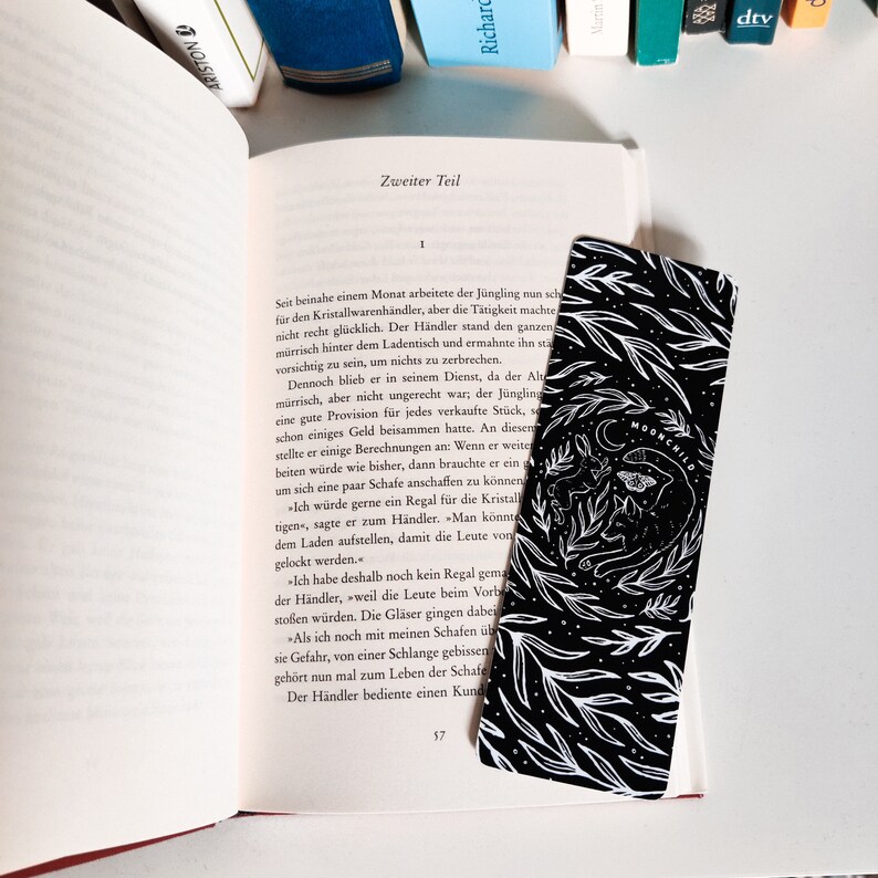 May include: Black and white bookmark with a floral design and the text "Moonchild".
