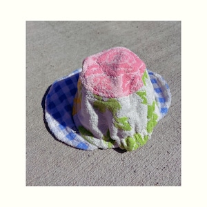 May include: A pink, green, and blue patterned bucket hat made from a soft, terry cloth material.