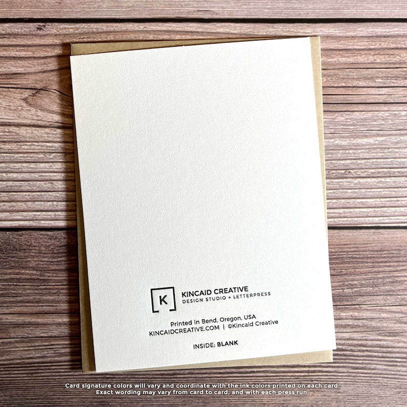 May include: The back of a blank greeting card with a brown envelope. The card has a white background with black text that reads "Kincaid Creative Design Studio + Letterpress" and "Printed in Bend, Oregon, USA Kincaidcreative.com | &copy;Kincaid Creative Inside: Blank".