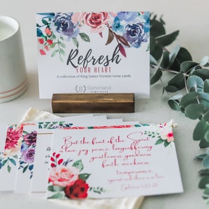 May include: A set of floral verse cards with the text "Refresh Your Heart" and "But the fruit of the Spirit is love, joy, peace, longsuffering, gentleness, goodness, faith, meekness, temperance, and patience." The cards are on a white surface with a candle and eucalyptus.